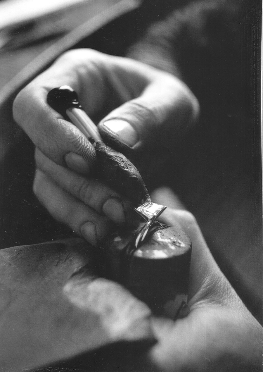 A jeweller's hands setting a diamond ring at the workbench